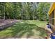 Lush backyard featuring a retaining wall, manicured lawn, and partial views of the home's exterior at 1005 Enderbury Dr, Raleigh, NC 27614