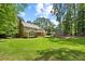 Spacious backyard with a well-manicured lawn, shed, and a full rear view of the home in a wooded setting at 1005 Enderbury Dr, Raleigh, NC 27614