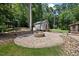 Inviting backyard featuring a brick patio with a fire pit, shed, and a blend of grass and wooded areas at 1005 Enderbury Dr, Raleigh, NC 27614