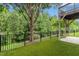 Green backyard with tall mature trees, an iron fence, and a covered patio area at 1034 Ventnor Pl, Cary, NC 27519