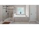Bright bathroom featuring a glass-enclosed shower, soaking tub, and a decorative window at 111 Revere Forest Ct, Cary, NC 27519