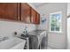 Well-lit laundry room features gray washer and dryer plus storage cabinets and sink at 111 Revere Forest Ct, Cary, NC 27519