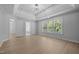 Bedroom featuring hardwood floors, tray ceiling, and bright windows at 114 Council Gap Ct, Cary, NC 27513