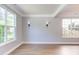 Empty living room featuring new floors, two bright windows, and modern lighting fixtures at 12320 Tetons Ct, Durham, NC 27703