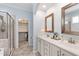 Bright bathroom with a double vanity, neutral tile, glass shower, and a walk-in closet at 1304 Rodessa Run, Raleigh, NC 27607