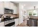 Open kitchen featuring stainless appliances, stone backsplash, white cabinets and eat in kitchen area at 1304 Rodessa Run, Raleigh, NC 27607