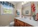 Cozy bathroom with cherry wood vanity, white countertop, decorative mirror, and window at 1304 Sandpiper Ct, Raleigh, NC 27615