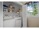 Bright laundry room with white washer and dryer, storage shelves, and natural light from the window at 1304 Sandpiper Ct, Raleigh, NC 27615