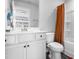 Clean bathroom features a white vanity, toilet, and a shower with orange curtain at 132 Yellow River Way, Garner, NC 27529