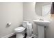Cozy powder room featuring a pedestal sink, toilet, and round mirror at 132 Yellow River Way, Garner, NC 27529