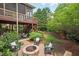 Cozy backyard featuring a brick fire pit and an elevated deck, surrounded by green landscaping at 1504 Hemlock Hill Dr, Durham, NC 27703