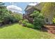 View of the home's backyard featuring a screened in porch, lush landscaping, and an open grass area at 1504 Hemlock Hill Dr, Durham, NC 27703
