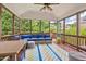 Inviting screened porch features comfortable seating, a ceiling fan, and a view of the lush greenery at 1504 Hemlock Hill Dr, Durham, NC 27703