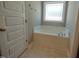 Bright bathroom features a soaking tub under a window, tile floors, and neutral decor at 160 Inverness St, Zebulon, NC 27597
