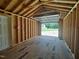 Unfinished interior with wooden walls and open garage door leading to the outdoors at 160 Inverness St, Zebulon, NC 27597