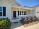 Charming porch with black door, white railing, and lush flowerbed in front of the home at 160 Inverness St, Zebulon, NC 27597