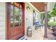 Inviting front porch featuring a cozy bench, a charming milk can and a beautiful wood door at 2218 Watersglen Dr, Apex, NC 27502