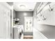 Well-lit laundry room featuring modern white washer and dryer, hooks, shelving, and a bright window at 2218 Watersglen Dr, Apex, NC 27502