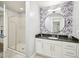 Modern bathroom featuring a shower with glass door and vanity with round mirror and floral wallpaper at 222 Glenwood Ave # 213, Raleigh, NC 27603