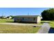 Back exterior of the home with gravel driveway, small porch, and grassy backyard at 2232 Tarboro Road Rd, Youngsville, NC 27596
