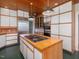 Modern kitchen with stainless appliances, cooktop island, and wooden paneled ceiling at 2400 Fairview Rd, Raleigh, NC 27608