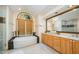 Bathroom featuring a soaking tub, tile flooring, wooden cabinets, and modern mirror at 2612 Scarlet Sage Ct, Raleigh, NC 27613