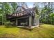 Exterior view of the house with a walk-out basement, deck, wooded surroundings, and green mossy ground at 2612 Scarlet Sage Ct, Raleigh, NC 27613