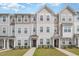 Charming townhomes boast diverse siding, manicured lawns, and inviting walkways under a partly cloudy blue sky at 2708 Chert Ln, Raleigh, NC 27610