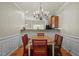 Dining area boasts hardwood floors, wainscoting, and a stylish chandelier connecting to the kitchen at 276 Linden Park Ln, Cary, NC 27519