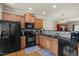 Well-lit kitchen boasts wood cabinets, sleek black appliances, and a functional layout for culinary enthusiasts at 276 Linden Park Ln, Cary, NC 27519