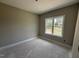 Cozy bedroom with neutral paint and a large window overlooking the yard with unfinished flooring at 2776 Rains Mill Rd, Princeton, NC 27569