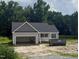 A newly built home with a gray exterior, an open garage and a dark roof with some landscaping to be completed at 2776 Rains Mill Rd, Princeton, NC 27569