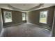Spacious main bedroom with tray ceiling, neutral paint, and three windows overlooking the front yard with unfinished floors at 2776 Rains Mill Rd, Princeton, NC 27569