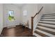 Inviting entryway with dark wood floors, staircase, and a bench seat under a window, creating a warm welcome at 3053 Roy Ct, Apex, NC 27523