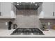Close-up of stove and backsplash with modern appliances, stylish gray backsplash, and elegant quartz countertops at 3053 Roy Ct, Apex, NC 27523