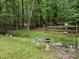 Lush backyard oasis with a stream, mature trees, birdbath and a charming bird feeder at 308 Trappers Sack Rd, Cary, NC 27513
