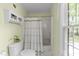 Bright bathroom featuring a shower-tub combo and storage cabinet, illuminated by natural light from a nearby window at 308 Trappers Sack Rd, Cary, NC 27513