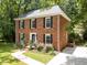 Elegant brick home featuring lush landscaping, a well-manicured lawn, and black shutters at 308 Trappers Sack Rd, Cary, NC 27513