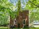The back exterior of a two-story brick home is surrounded by lush greenery at 308 Trappers Sack Rd, Cary, NC 27513