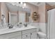 Stylish bathroom with double vanity, decorative mirror, pink wallpaper and wainscoting at 3181 Zebroid Way, New Hill, NC 27562