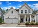 Charming two-story white farmhouse with a welcoming front porch and manicured landscaping at 3181 Zebroid Way, New Hill, NC 27562