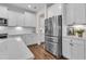 View of the kitchen with stainless steel refrigerator and white cabinets; hardwood floors at 3181 Zebroid Way, New Hill, NC 27562
