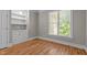 Bedroom with hardwood floors, built-in shelving and a large window with an exterior view at 3600 Trail 23 St, Durham, NC 27707