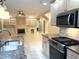 Open-concept kitchen featuring stainless steel appliances and a view of the living area with fireplace and built-in shelves at 3600 Trail 23 St, Durham, NC 27707