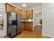 Cozy kitchen featuring stainless steel refrigerator, wooden cabinets, and hardwood floors at 400 Indian Elm Ln, Cary, NC 27519
