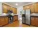 Well-lit kitchen featuring stainless steel appliances, wooden cabinets, and a view into the breakfast nook at 400 Indian Elm Ln, Cary, NC 27519