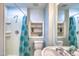 Bright bathroom featuring a shower with blue curtain, toilet, vanity, and a built-in shelf with decorative items at 405 Widdington Ln, Cary, NC 27519