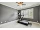 Bright bedroom featuring a treadmill, dark accent wall, and a window with plantation shutters at 4221 Bibleway Ct, Holly Springs, NC 27540