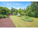 Expansive backyard featuring lush lawn, mature trees, landscaping, and a storage shed at 425 Cottonseed Way, Durham, NC 27703