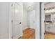 Hallway with wood floors leading to the bathroom with white cabinets and black hardware at 444 S Blount St # 209, Raleigh, NC 27601